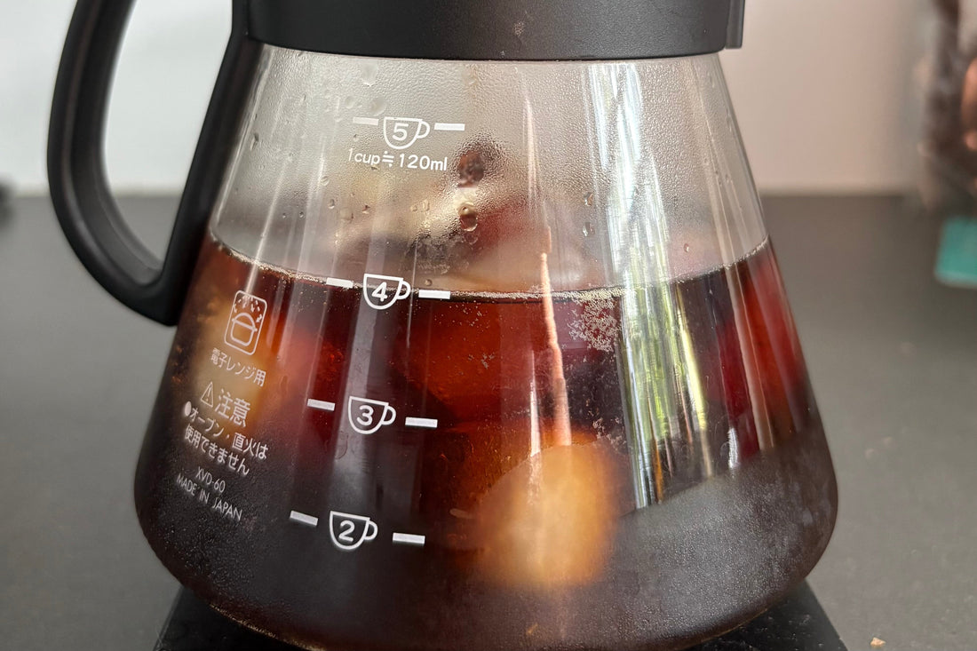 Pitcher of cold coffee with ice cubes.