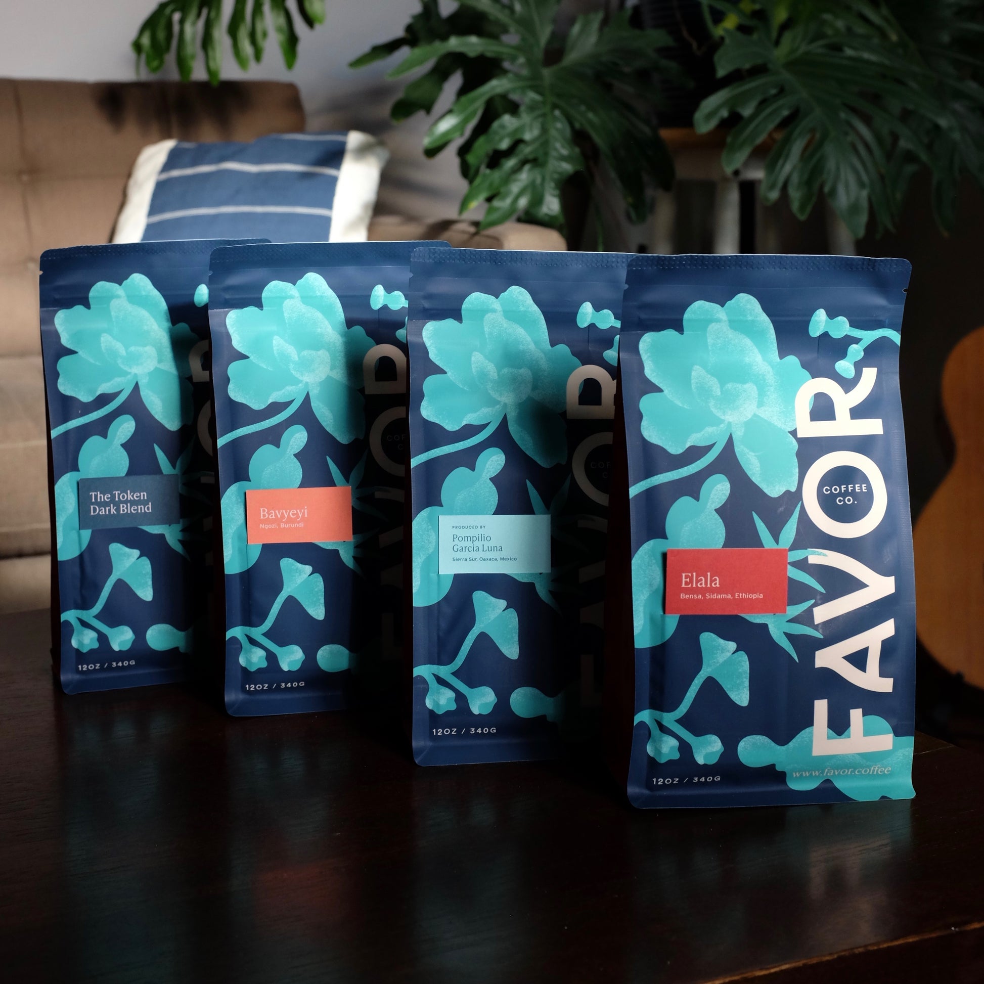Four bags of coffee from Favor with a blue floral design. There is a navy blue, pink, teal and red color tag on each bag.