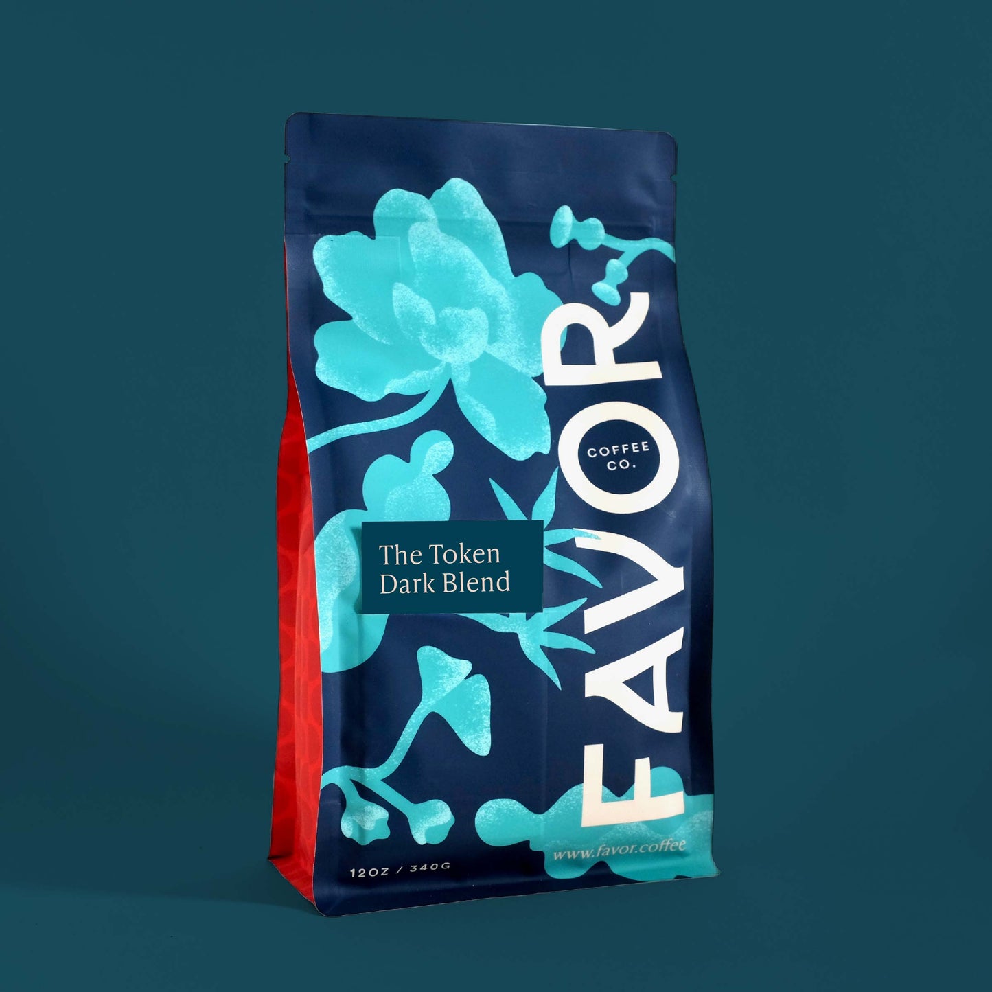 A bag of coffee labeled 'The Token Dark Blend' from Favor Coffee Co. Bag has a blue floral design on a dark blue background