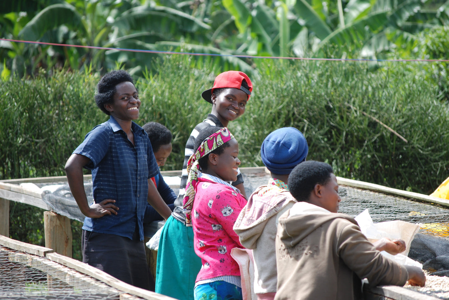 Women smiling while standing next to coffee drying beds